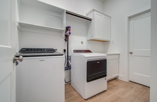 clothes washing area featuring cabinet space, wood tiled floor, and independent washer and dryer