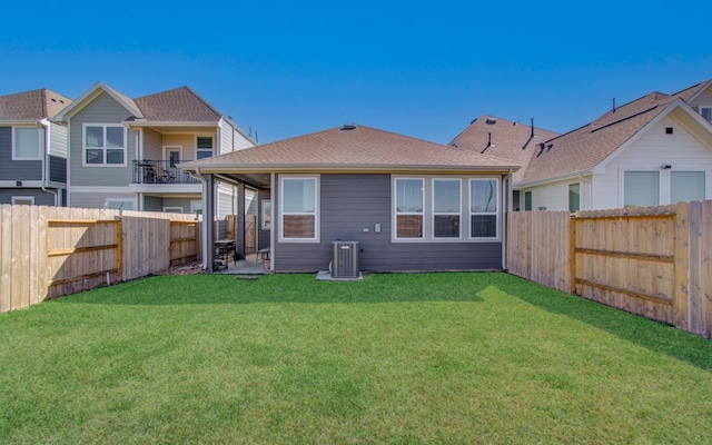 rear view of property featuring a yard, central AC, and a fenced backyard