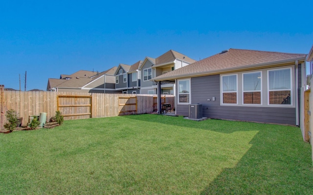 view of yard featuring a residential view, central AC, and a fenced backyard