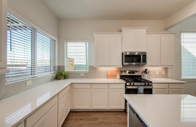 kitchen with stainless steel appliances, light countertops, decorative backsplash, and white cabinetry