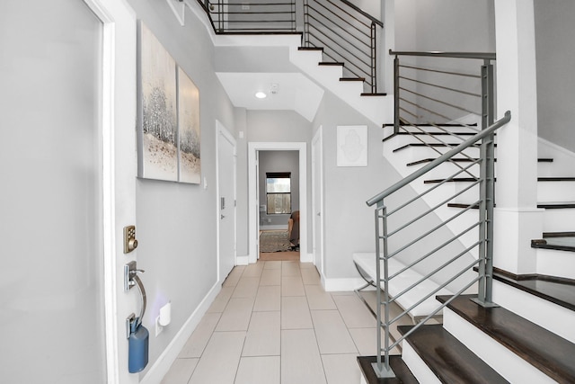 foyer featuring stairs, light tile patterned flooring, and baseboards