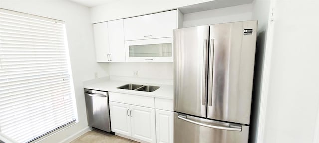 kitchen featuring light tile patterned floors, light countertops, appliances with stainless steel finishes, white cabinetry, and a sink