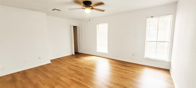 unfurnished room featuring ceiling fan, visible vents, baseboards, a wealth of natural light, and light wood finished floors