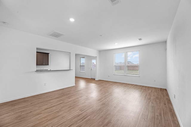 unfurnished living room featuring light wood-type flooring, baseboards, and visible vents