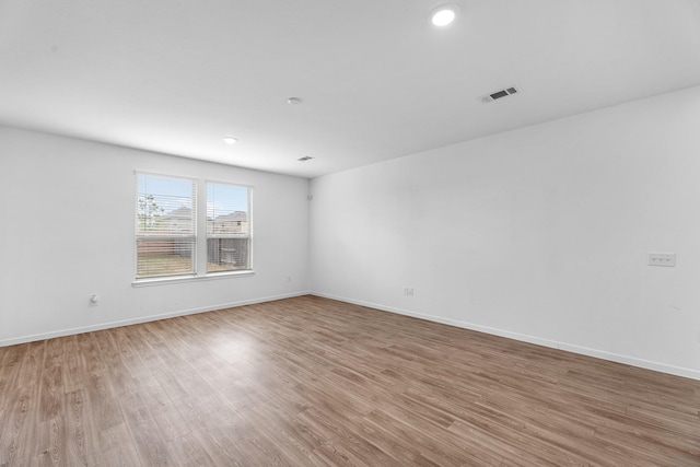 unfurnished room with light wood-style flooring, visible vents, and baseboards