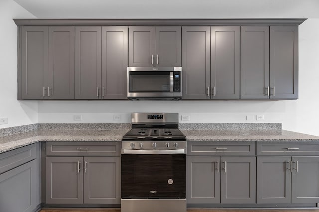 kitchen featuring appliances with stainless steel finishes, light stone counters, and gray cabinetry