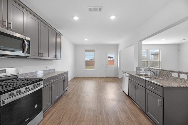 kitchen with visible vents, light wood-style flooring, light stone counters, stainless steel appliances, and gray cabinetry