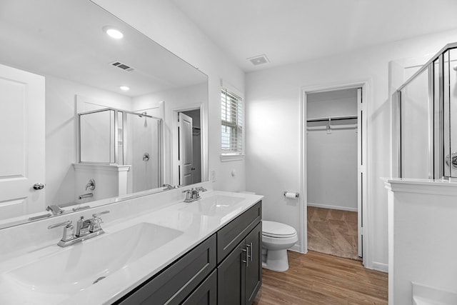 bathroom with a walk in closet, visible vents, and a sink