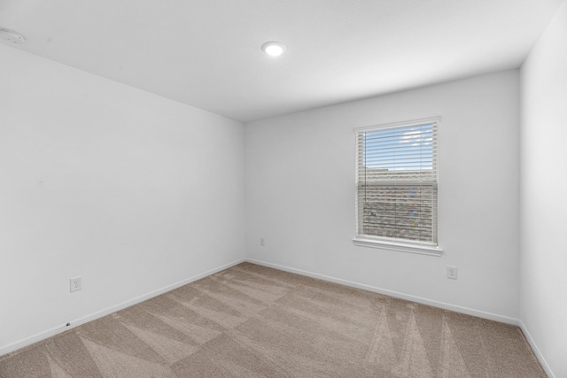 spare room featuring baseboards and light colored carpet