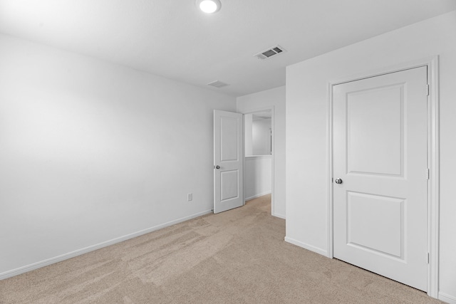 unfurnished bedroom featuring visible vents, light carpet, and baseboards