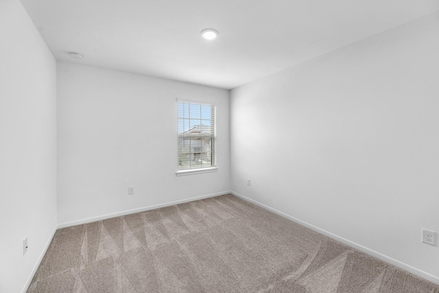 empty room featuring baseboards and light colored carpet