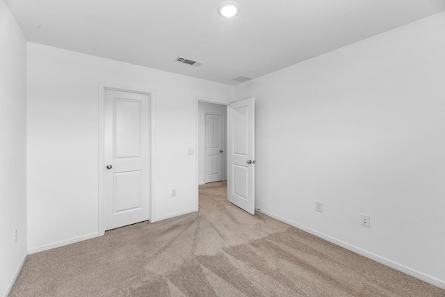 unfurnished bedroom with visible vents, light carpet, and baseboards