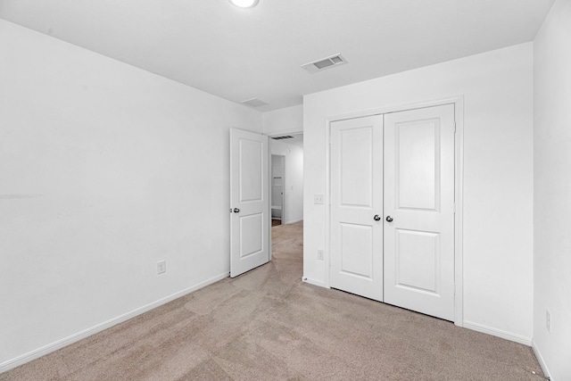 unfurnished bedroom featuring a closet, visible vents, light carpet, and baseboards