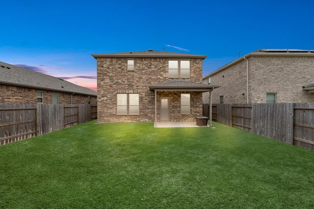 back of property with brick siding, a fenced backyard, a lawn, and a patio