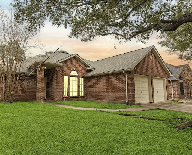 ranch-style home featuring a garage, brick siding, driveway, roof with shingles, and a lawn