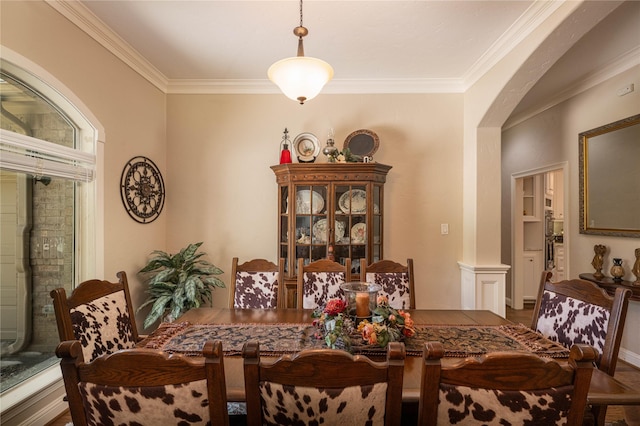 dining space with arched walkways and crown molding