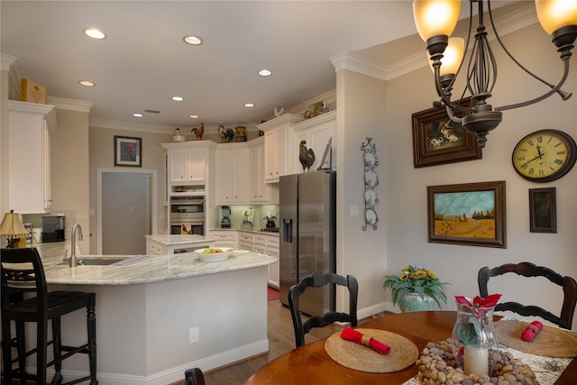 kitchen with ornamental molding, a peninsula, appliances with stainless steel finishes, and white cabinets