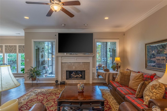 living room with a fireplace, a ceiling fan, crown molding, and wood finished floors