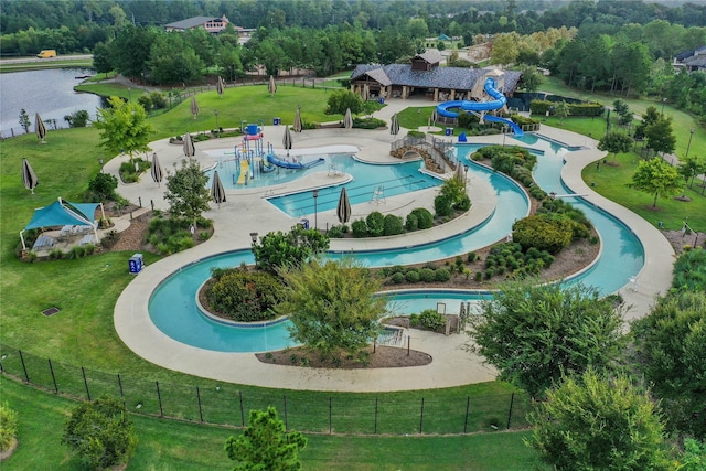 view of swimming pool with a water view, fence, and a yard