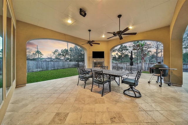 view of patio with outdoor dining space, a fenced backyard, grilling area, and a tile fireplace