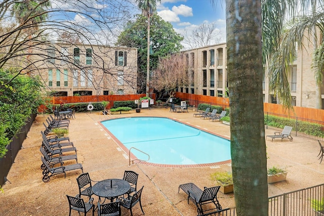 community pool with a patio area and fence