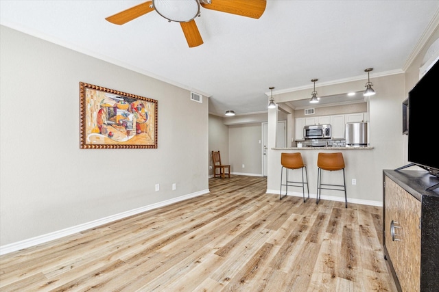 living room featuring visible vents, ornamental molding, a ceiling fan, light wood-type flooring, and baseboards