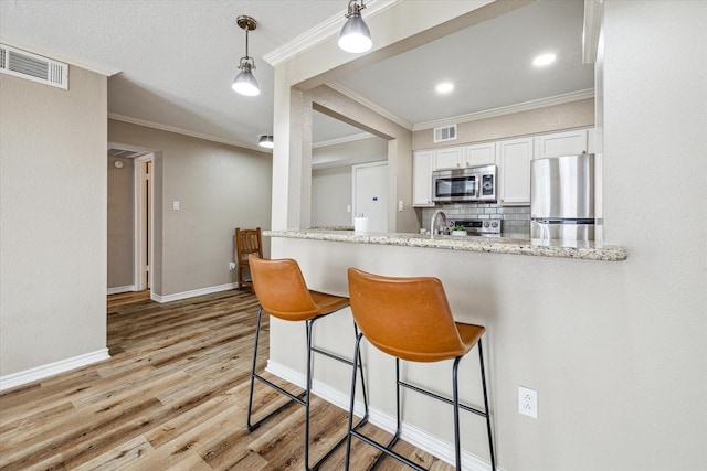 kitchen with visible vents, light wood-style flooring, light stone counters, stainless steel appliances, and white cabinetry