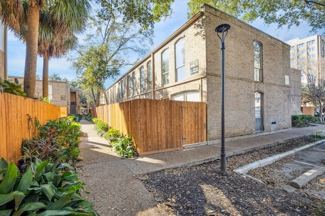 view of side of property featuring brick siding and fence