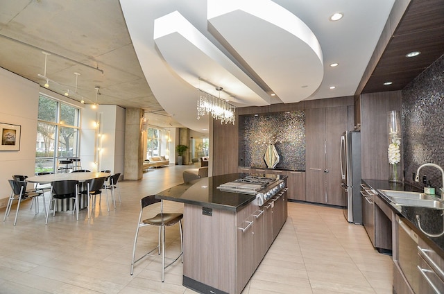 kitchen featuring a spacious island, modern cabinets, appliances with stainless steel finishes, a breakfast bar, and backsplash