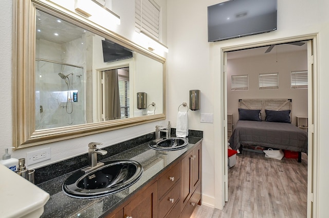 bathroom featuring double vanity, a shower stall, a sink, and wood finished floors