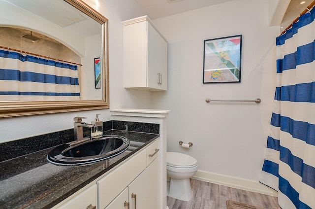 bathroom with baseboards, toilet, a shower with curtain, wood finished floors, and vanity