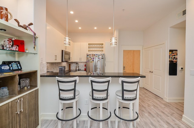 kitchen with dark countertops, a peninsula, stainless steel appliances, open shelves, and backsplash