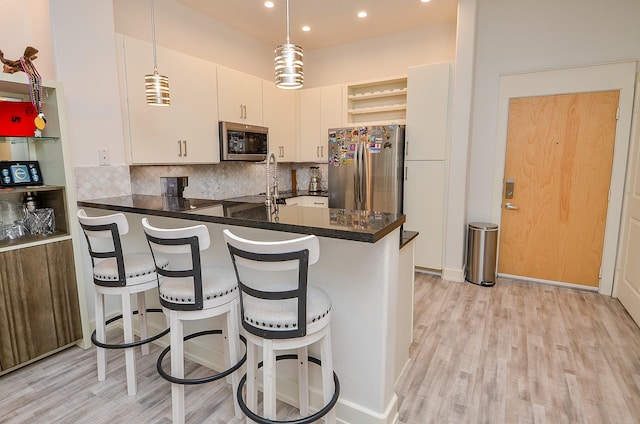 kitchen featuring stainless steel appliances, a peninsula, backsplash, open shelves, and dark countertops