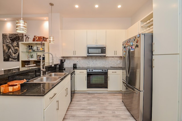 kitchen with tasteful backsplash, a peninsula, black appliances, white cabinetry, and a sink