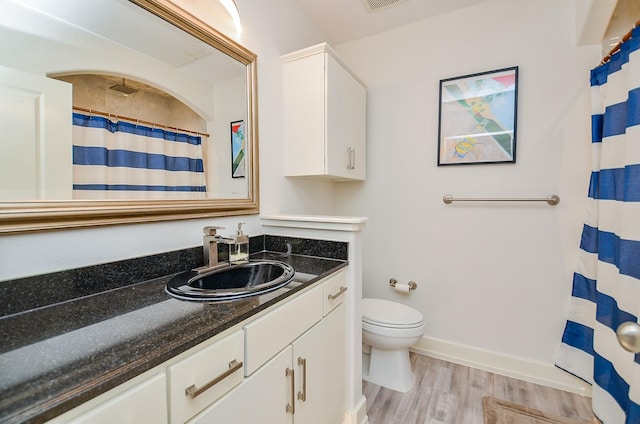 bathroom featuring visible vents, toilet, vanity, wood finished floors, and baseboards