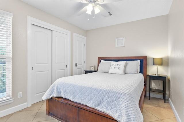 bedroom with a ceiling fan, a closet, light tile patterned flooring, and baseboards