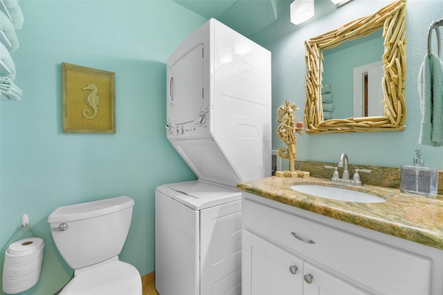 bathroom featuring toilet, stacked washer / drying machine, and vanity