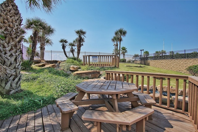 deck with outdoor dining area, a fenced backyard, and a yard