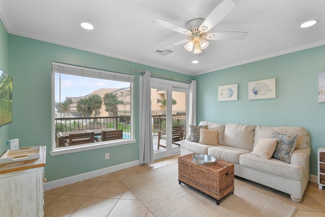 living room with light tile patterned floors, a ceiling fan, visible vents, baseboards, and crown molding