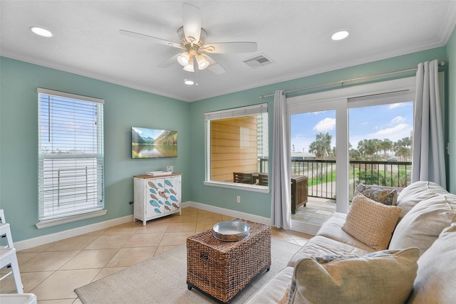 living room with crown molding, light tile patterned floors, visible vents, ceiling fan, and baseboards