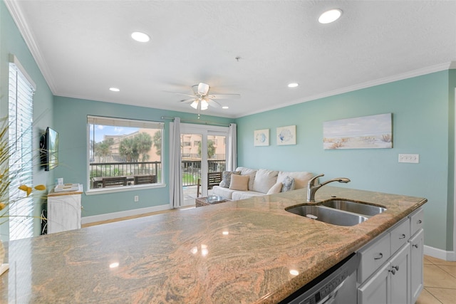 kitchen featuring stone counters, ornamental molding, open floor plan, and a sink