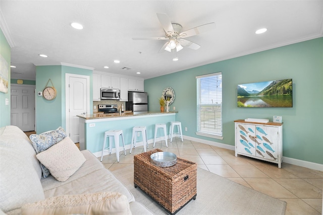 living room with light tile patterned floors, recessed lighting, ornamental molding, a ceiling fan, and baseboards