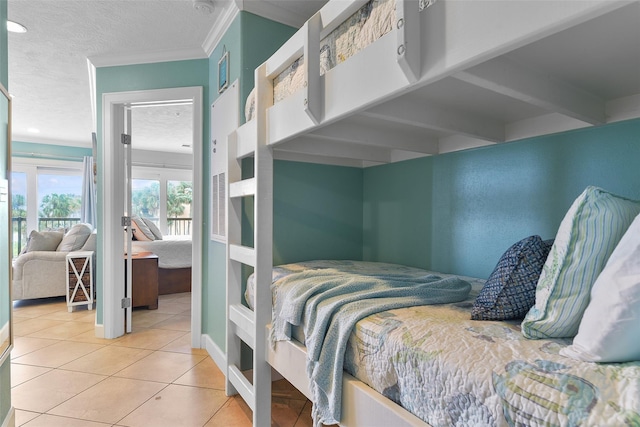 bedroom with ornamental molding, a textured ceiling, baseboards, and tile patterned floors