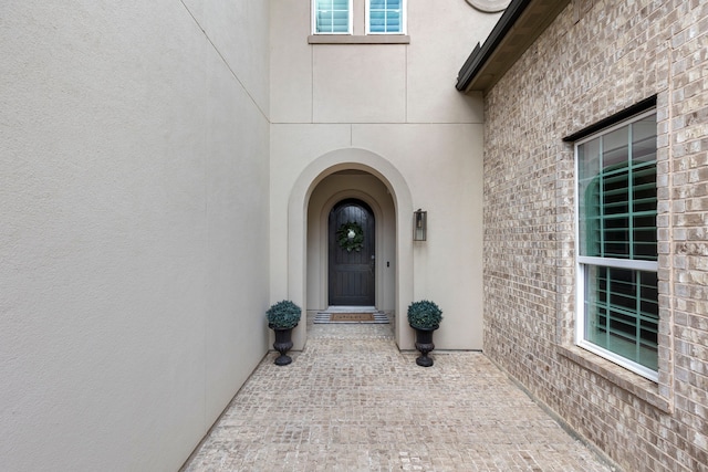 property entrance with brick siding and stucco siding