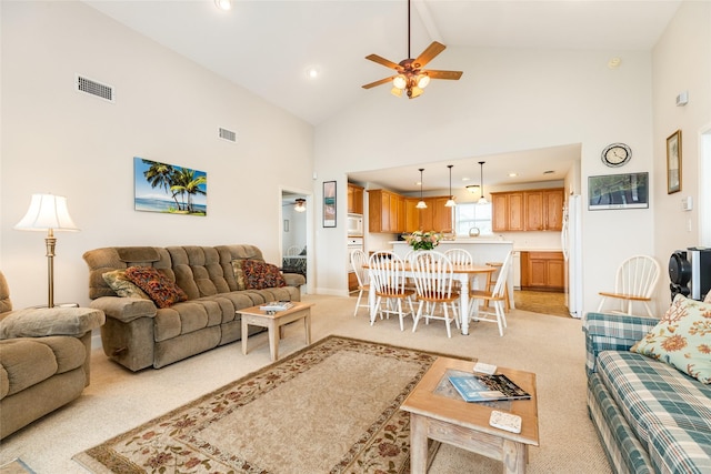 living area featuring light carpet, high vaulted ceiling, ceiling fan, and visible vents