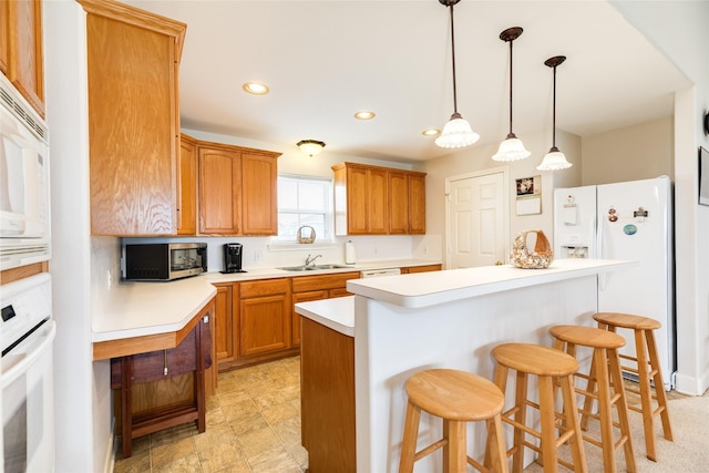 kitchen with a center island, pendant lighting, light countertops, white appliances, and a kitchen bar