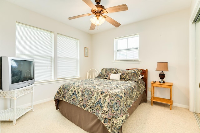 bedroom featuring light carpet, a closet, a ceiling fan, and baseboards