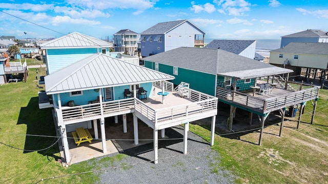 rear view of property featuring metal roof, roof with shingles, a standing seam roof, a wooden deck, and a carport