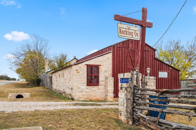 exterior space featuring stone siding, a yard, a detached garage, and fence