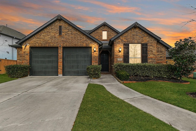 view of front of property with a garage, a yard, concrete driveway, and brick siding